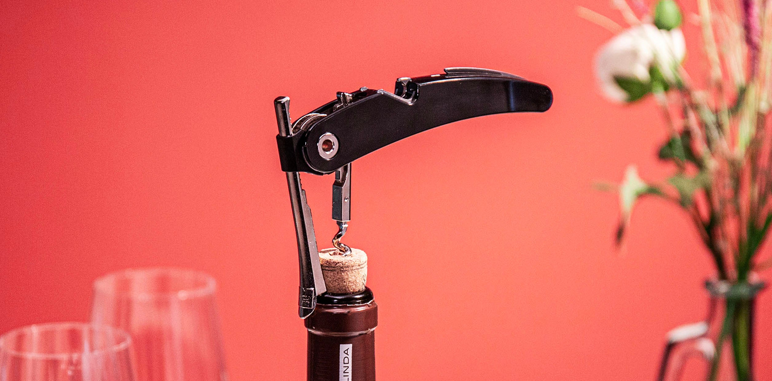 Tire-bouchon professionnel à levier posé près d'une bouteille de vin débouchée